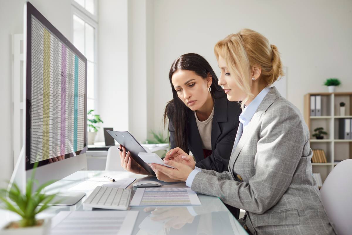 Young business people company employees having discussion about financial data analyzing company accounting on meeting. Woman accountant working on pc with charts and talking with colleague.